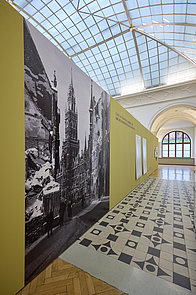grüne Wand mit Fototapete des zerstörten Rathauses und Texten