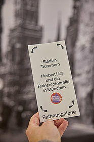 Hand hält Ausstellungsflyer
