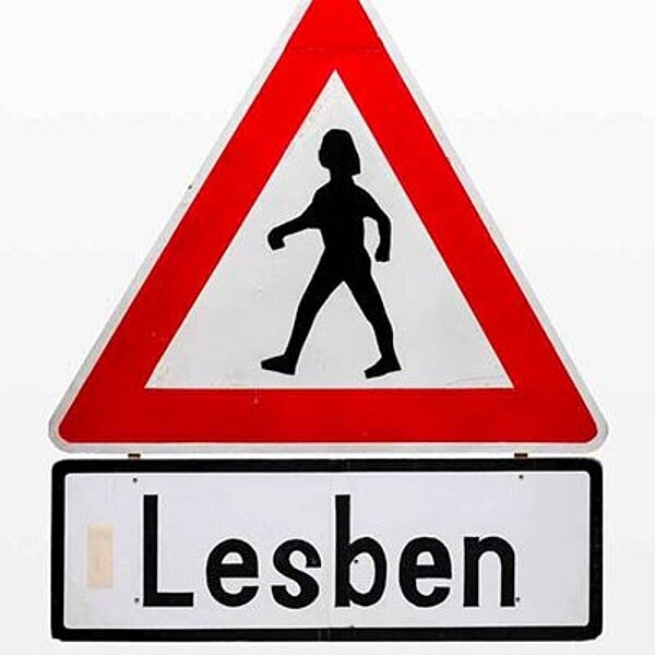 Verkehrszeichen mit einer gehenden Figur in der Mitte und dem Hinweiß„Lesben
