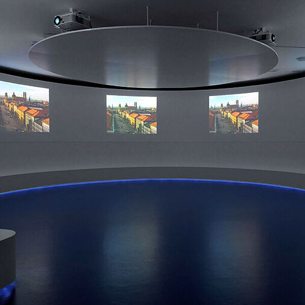 Ansicht eines runden Raumes mit vier gleichen Videoprojektionen an der Wand.
