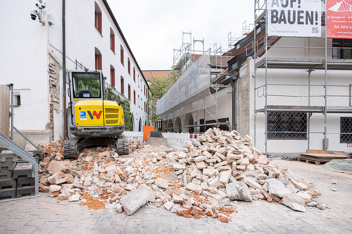 Baustelle mit eingerissener Mauer und Bagger